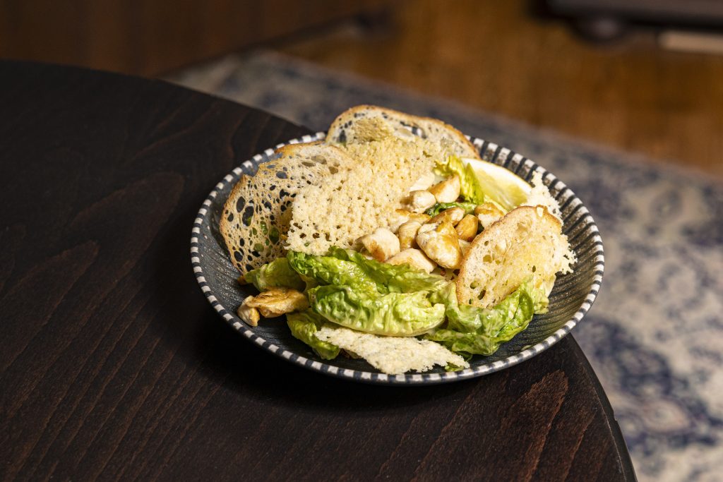 Insalata alla Cesare Csirkével "Római saláta, házi szardellás öntet, parmezán chips, ropogós kenyér, pirított pancetta csirkével"