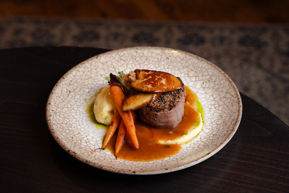 Bélszín steak grillezett francia kacsamájjal, burgonyapürével, serpenyős bébi répával, ropogós hagymával és pecsenyelével